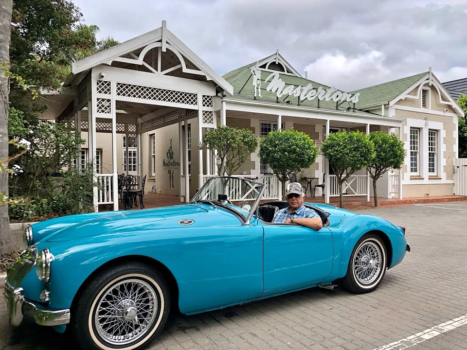 Flip van der Merwe at the wheel of his turquoise MGA 1500 roadster outside Mastertons, Port Elizabeth