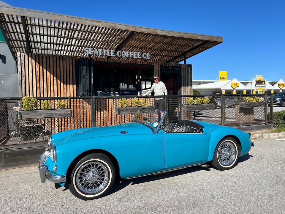 The MGA in bright sunshine outside a coffee shop